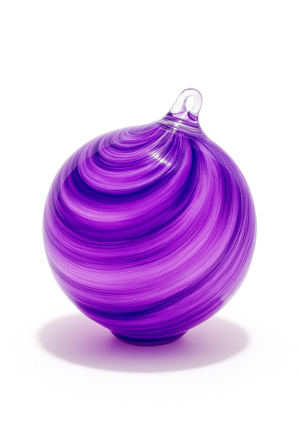 Hand-blown purple glass ornament with swirl design from Puget Sound Glassblowing Studio on a white background. 