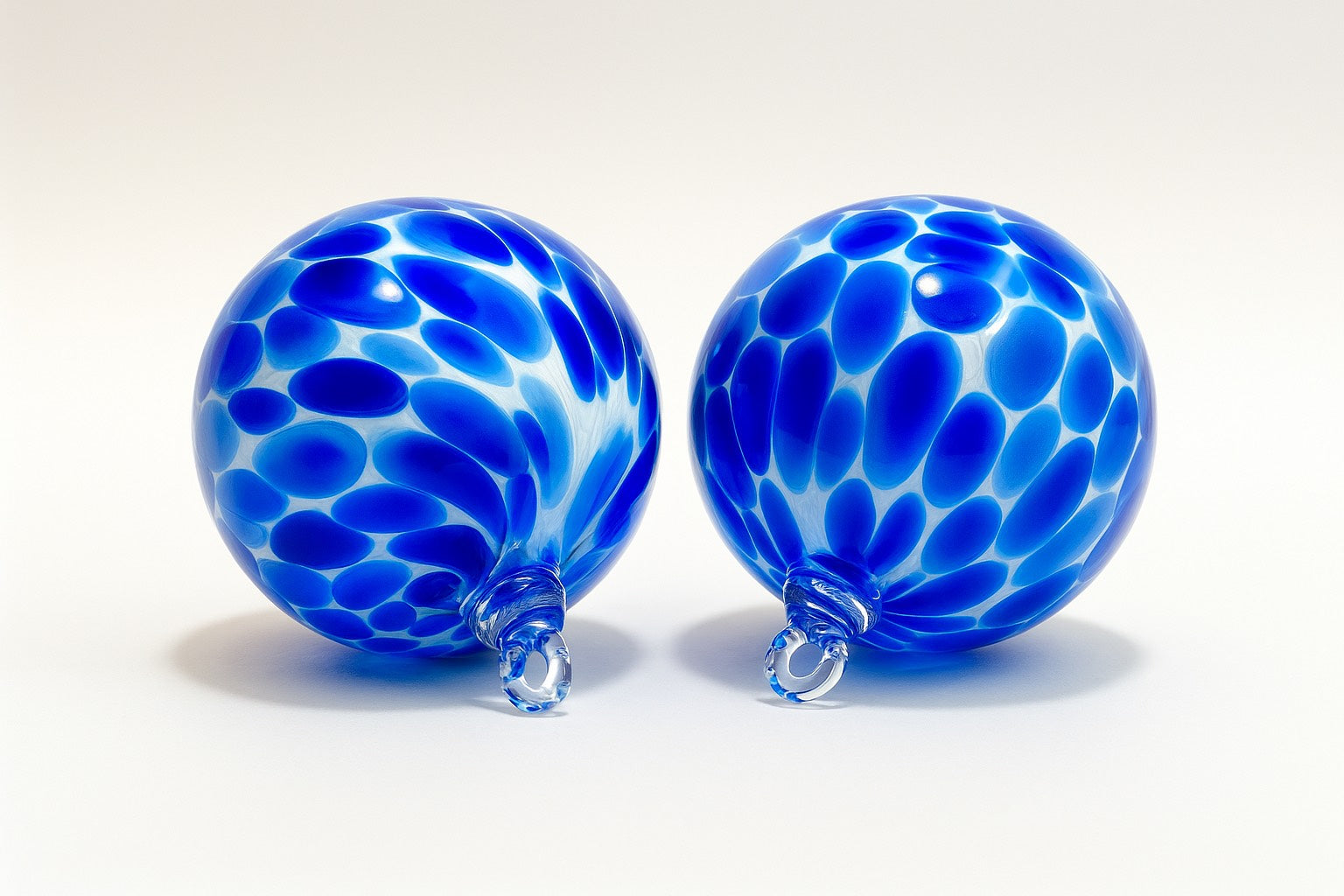 Two blue hand-blown glass ornaments with white speckled pattern by Puget Sound Glassblowing Studio.